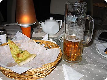 Bierglas, Brotkorb, Teekanne auf Tisch